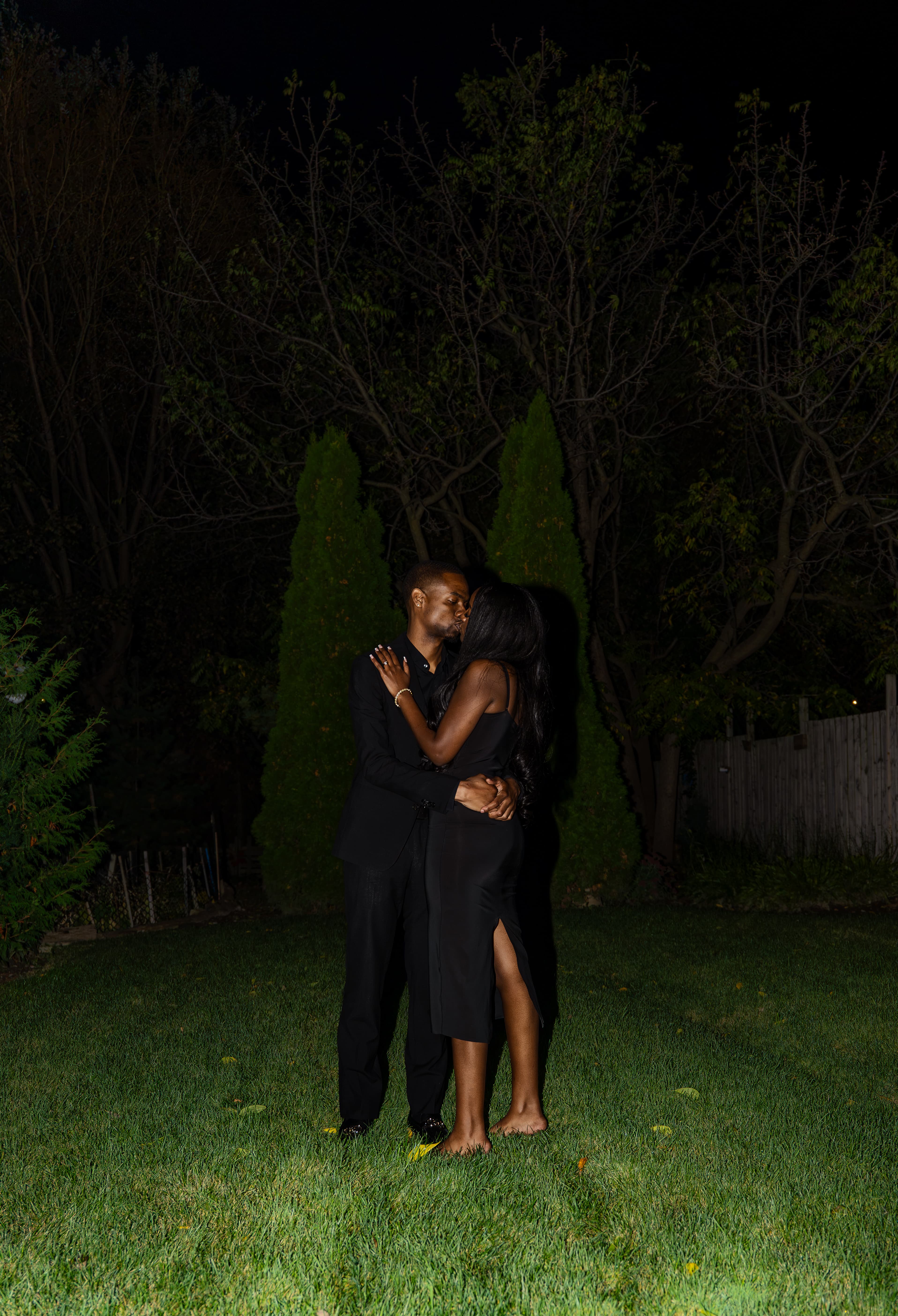 A couple sharing a quiet kiss beneath the trees
