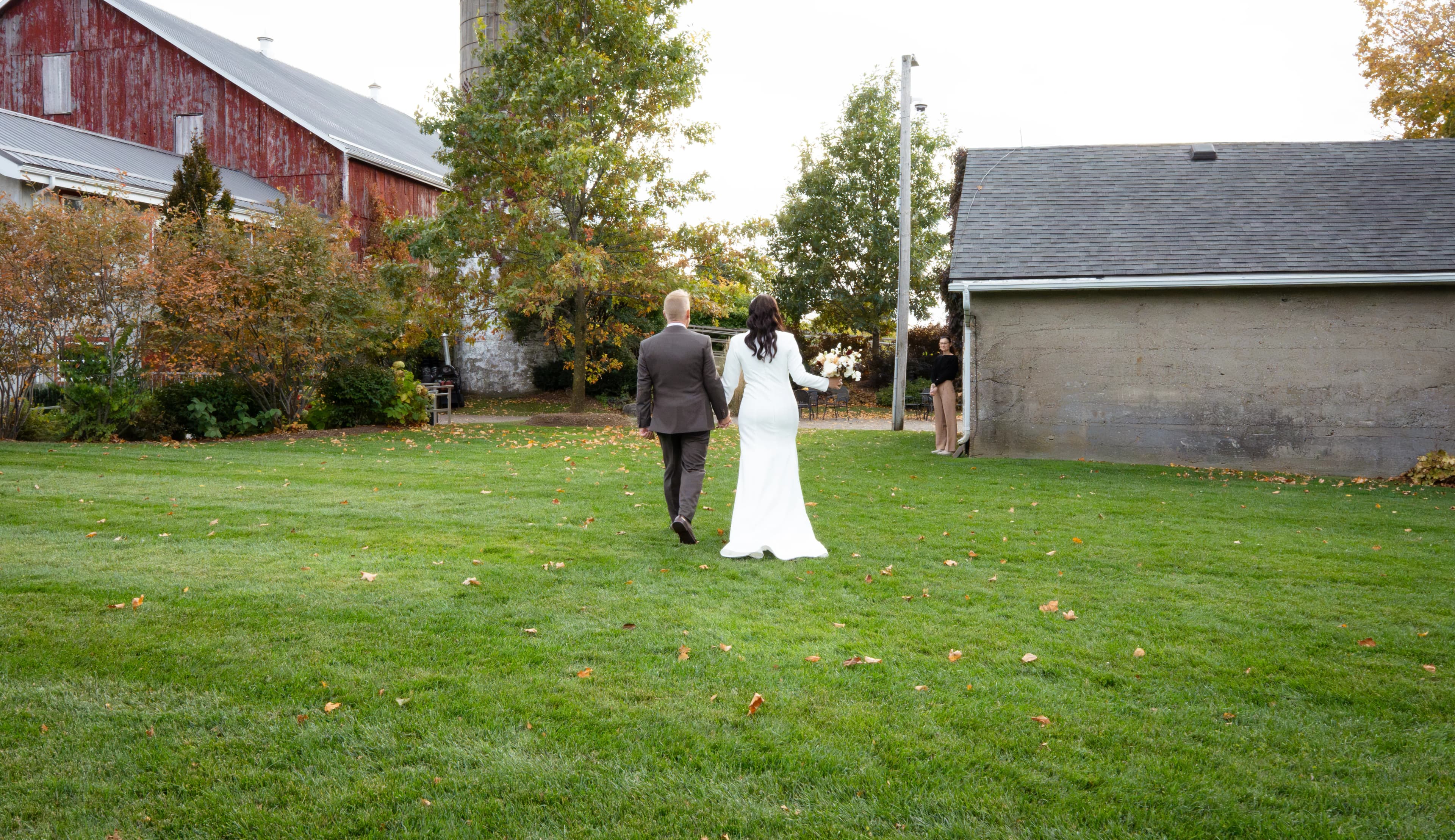 Newlyweds walking together across the grounds of a barn venue